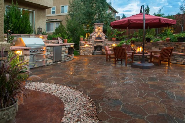 A patio area with a grilling station and fireplace